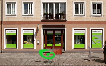 Fachgeschäft für Hörgeräte mit grüner Beschriftung und modernem Schaufensterdesign.